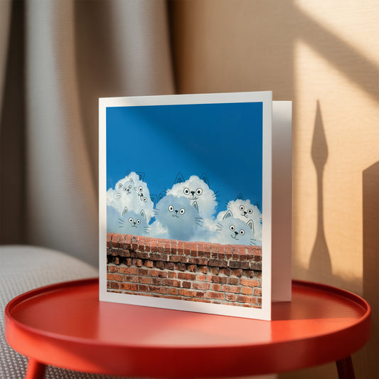 Greeting card with cartoon cats on a brick wall design, placed on a red table.