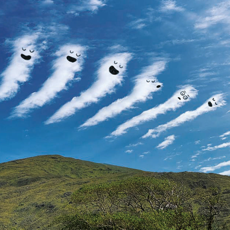 Clouds with faces against a blue sky with green hills below.