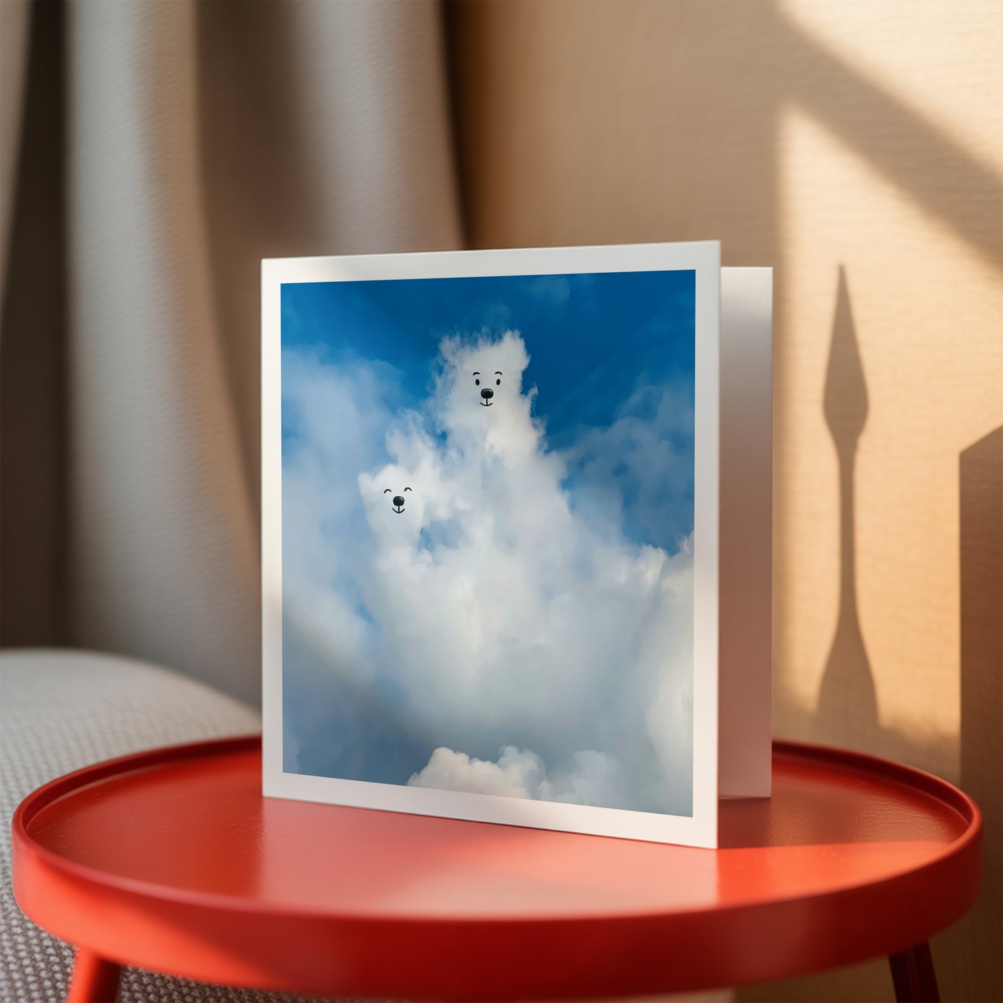 Greeting cards of two bears in a cloud with a blue sky on a red table.