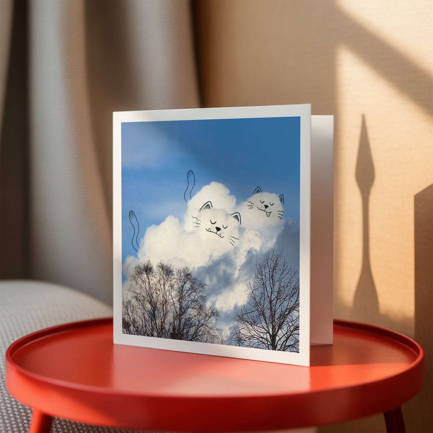 Greeting card with cloud and cat design on a red table