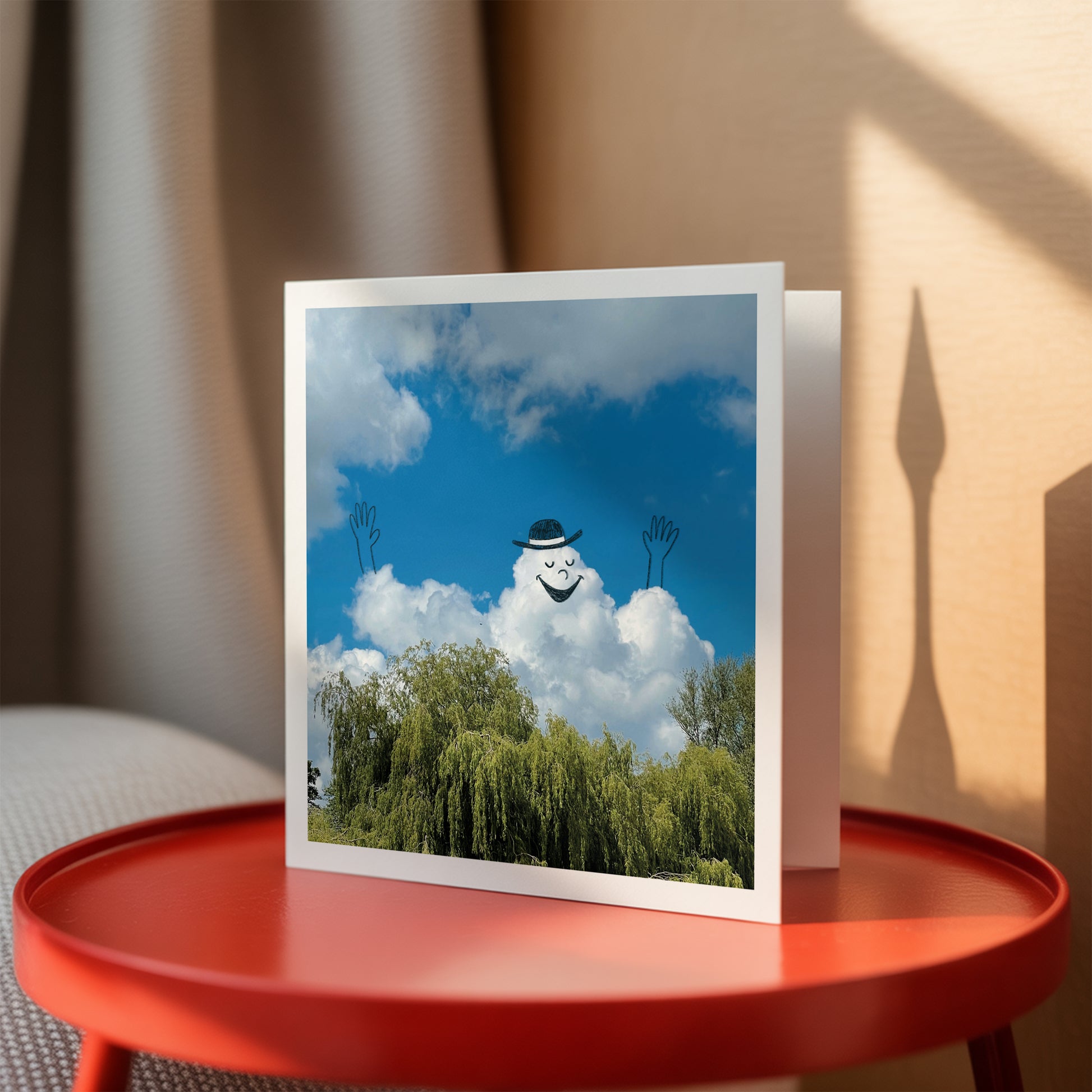 Greeting cards with a cloud with face against a blue sky on a red table.